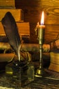 Inkwell with feather, old books and documents, a burning candle stands on a woodenÃÂ the table Royalty Free Stock Photo